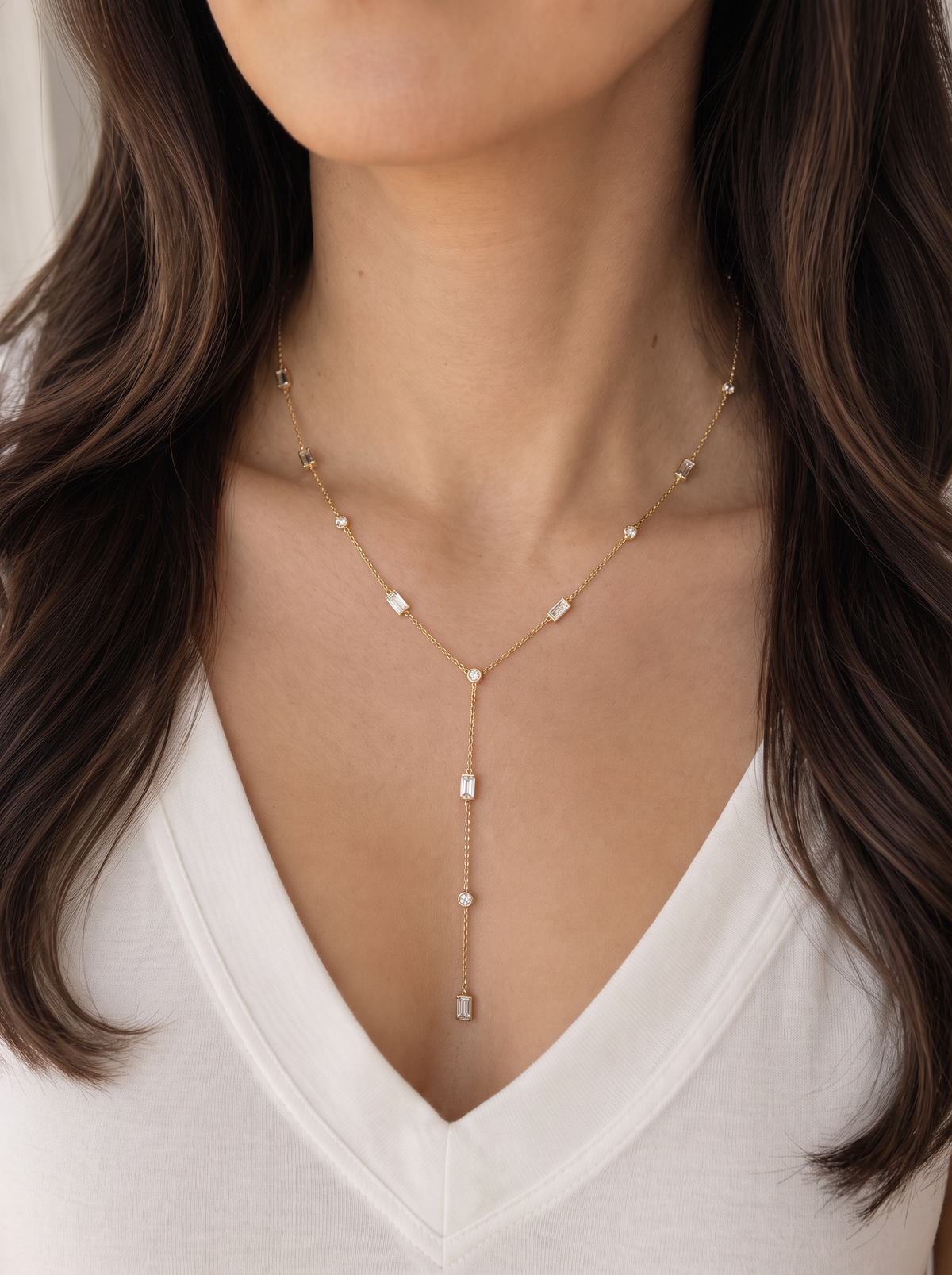 Close-up of a woman wearing the delicate A. Atelier Signature yellow gold diamond lariat with a white V-neck blouse.