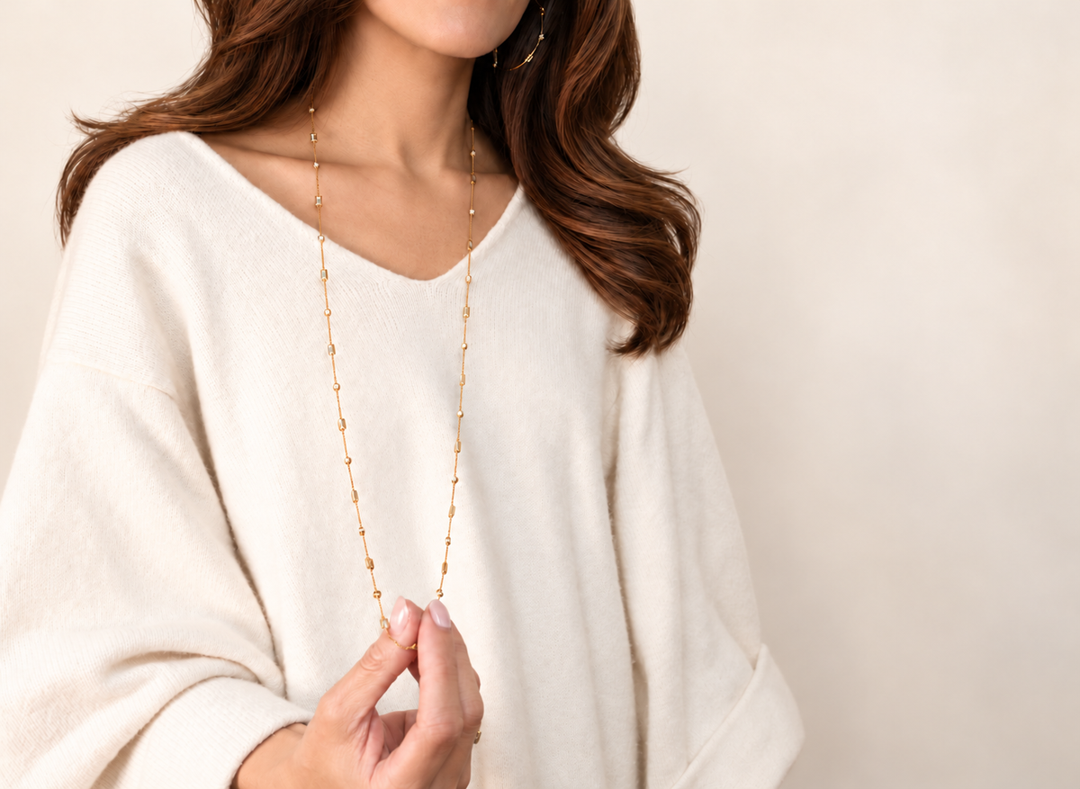 Woman wearing the delicate A. Atelier Signature Long Necklace in yellow gold over a white blouse.
