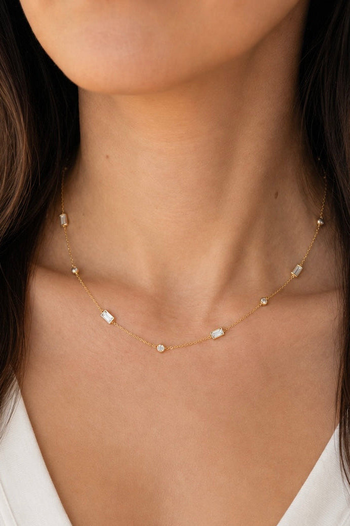 Angled close-up of the delicate A. Atelier Signature yellow gold choker showing its round and baguette diamonds, worn loosely.