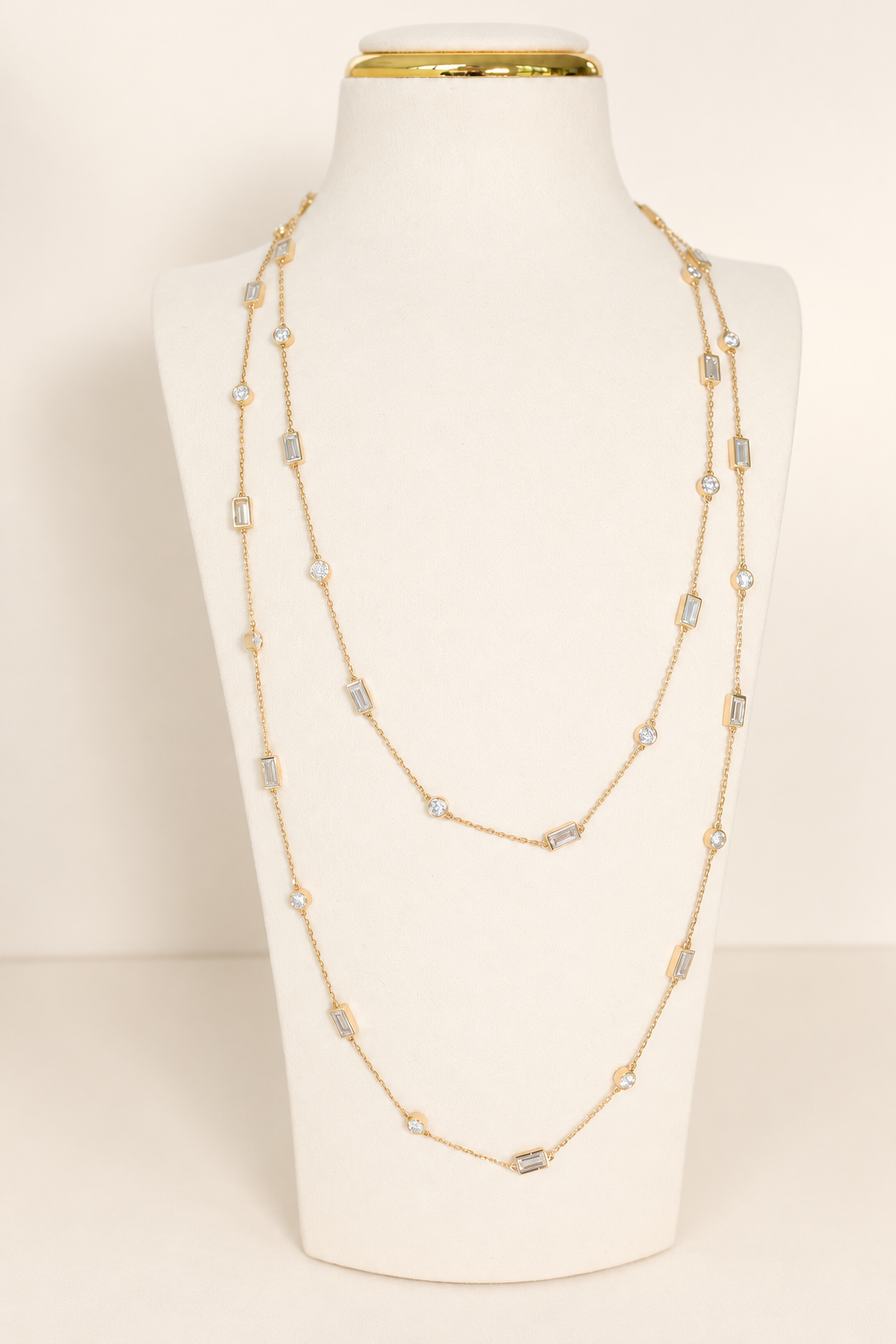 Delicate A. Atelier Signature Long Necklace in 18K yellow gold, doubled on a cream necklace stand.